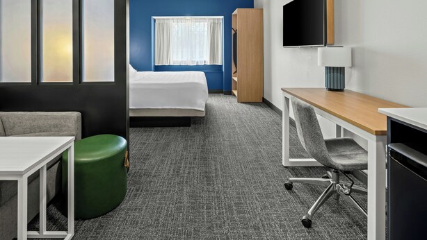 A hotel room with a bed, a desk, a chair, a TV, and a wardrobe. - Spark by Hilton Stillwater (Stillwater)