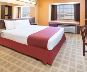A hotel room with a large bed, a window with curtains, a desk, and a chair. - Spark by Hilton Stillwater (Stillwater)