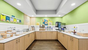 A modern kitchen with wooden cabinets, a white countertop, and various food items displayed on the wall. - Spark by Hilton Stillwater (Stillwater)