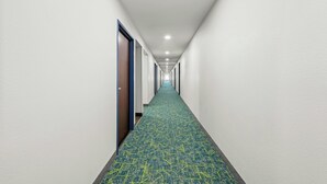 A long, narrow hotel corridor with a patterned carpet and doors on one side. - Spark by Hilton Stillwater (Stillwater)