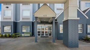 A building entrance with a covered area marked '423', a bench, and a clear sky. - Spark by Hilton Stillwater (Stillwater)