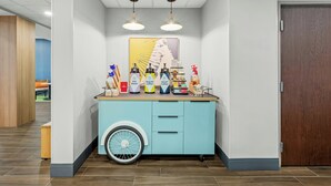A counter with beverage dispensers, a bicycle wheel, and a mirror. - Spark by Hilton Stillwater (Stillwater)