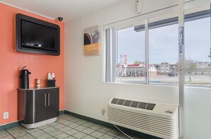 A hotel room with a TV, a small kitchenette, a window with a view of a gas station, and a wall-mounted heater. - Motel6 Topeka, KS - Northwest (Topeka)