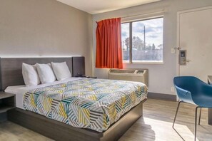 A hotel room with a bed, a window with curtains, a chair, and a thermostat. - Motel6 Topeka, KS - Northwest (Topeka)