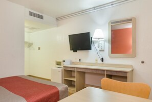 A hotel room with a bed, a desk, a television, a microwave, a lamp, and a mirror. - Motel6 Topeka, KS - Northwest (Topeka)