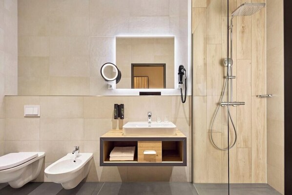 Une salle de bain moderne équipée d’un meuble-lavabo, d’un bidet et d’une douche.