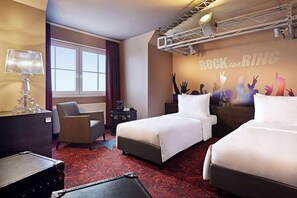 A hotel room with two beds, a desk, a chair, a lamp, a radiator, and a window. - Lindner Hotel Nurburgring Motorsport, Part of JDV by Hyatt (Nuerburg)