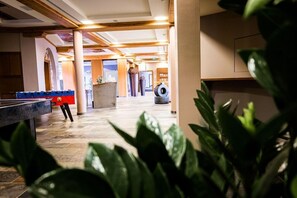 A lobby with a pool table, a large plant, and a tire in the background. - Lindner Hotel Nurburgring Motorsport, Part of JDV by Hyatt (Nuerburg)