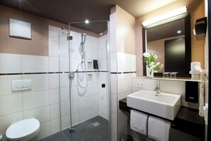 Une salle de bain moderne avec une douche à parois de verre, un lavabo blanc et des toilettes.