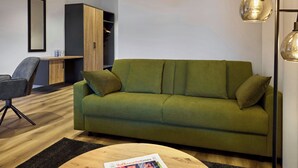 Uma sala de estar moderna com um sofá verde, uma mesa de centro de madeira e uma revista sobre ela.