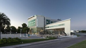 A modern hotel with a prominent entrance, a parking lot, and landscaped areas.