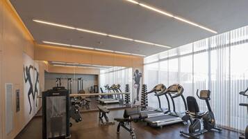 Ein modernes Fitnessstudio mit unterschiedlichen Trainingsgeräten, großen Fenstern und einem klaren, minimalistischen Design.