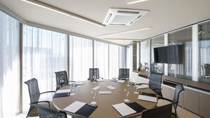 A conference room with a round table, chairs, and a television screen.