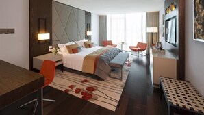 Una habitación de hotel moderna con una cama grande, un escritorio, una silla, una mesita y un banco.