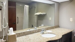 Baño con encimera de granito, lavamanos, espejo, toallero y secador de pelo.