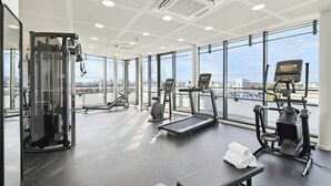 A gym with various exercise equipment, large windows, and a city view.