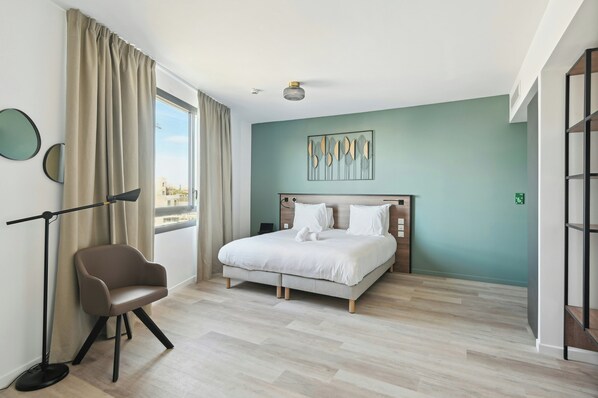 A modern bedroom with a bed, a chair, a floor lamp, and a view through the window. - All Suites Appart Hotel Paris Ouest Colombes (Colombes)