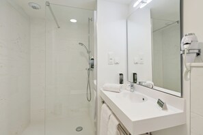 Une salle de bain moderne avec une douche à parois de verre, un lavabo blanc et un grand miroir.