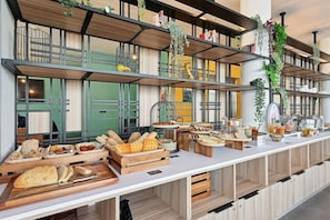A buffet setup with various food items and a modern interior design. - All Suites Appart Hotel Paris Ouest Colombes (Colombes)