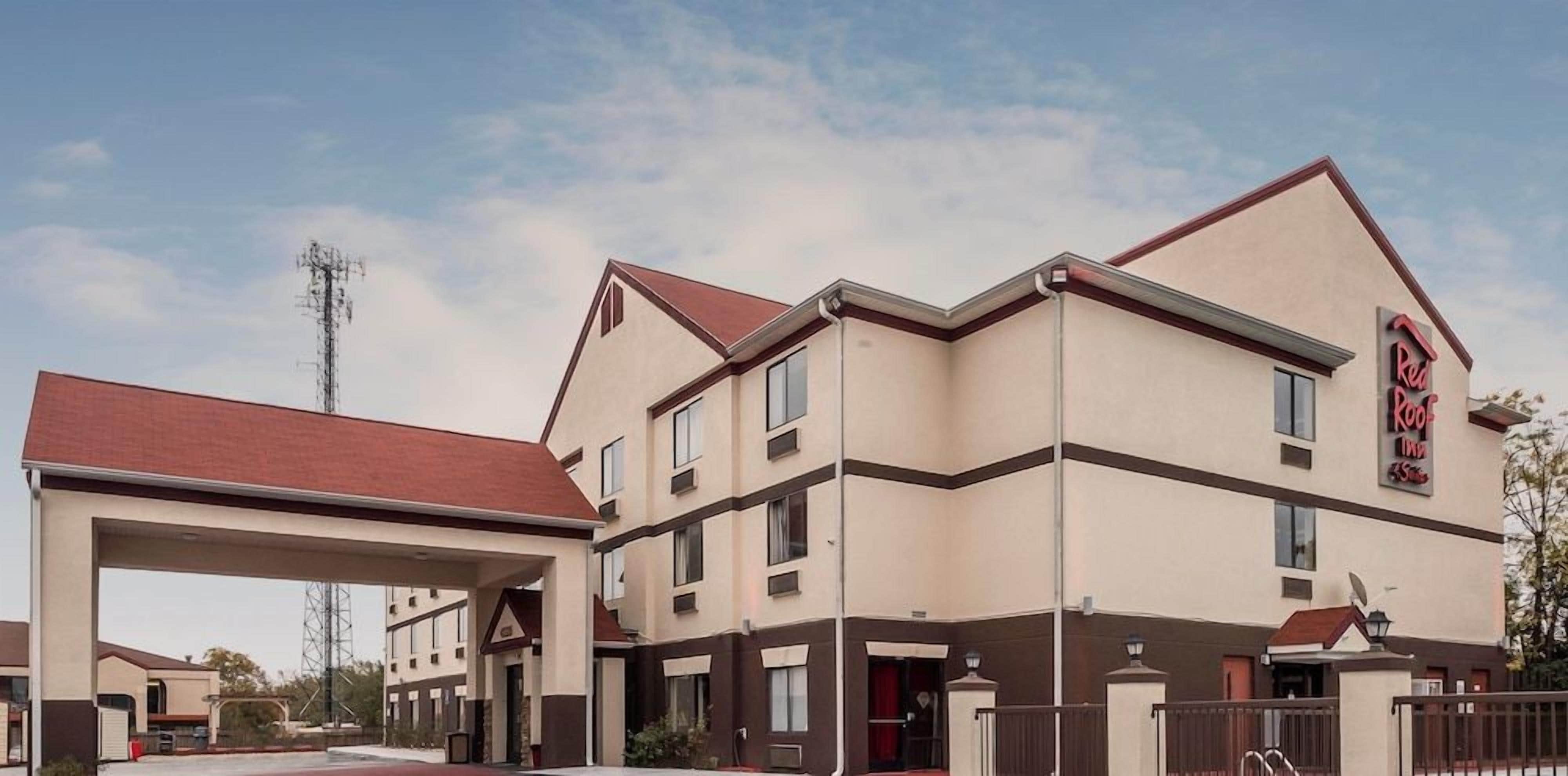 A Red Roof Inn with a two-story structure, a covered parking area, and a clear sky.