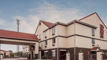 A Red Roof Inn with a two-story structure, a covered parking area, and a clear sky.