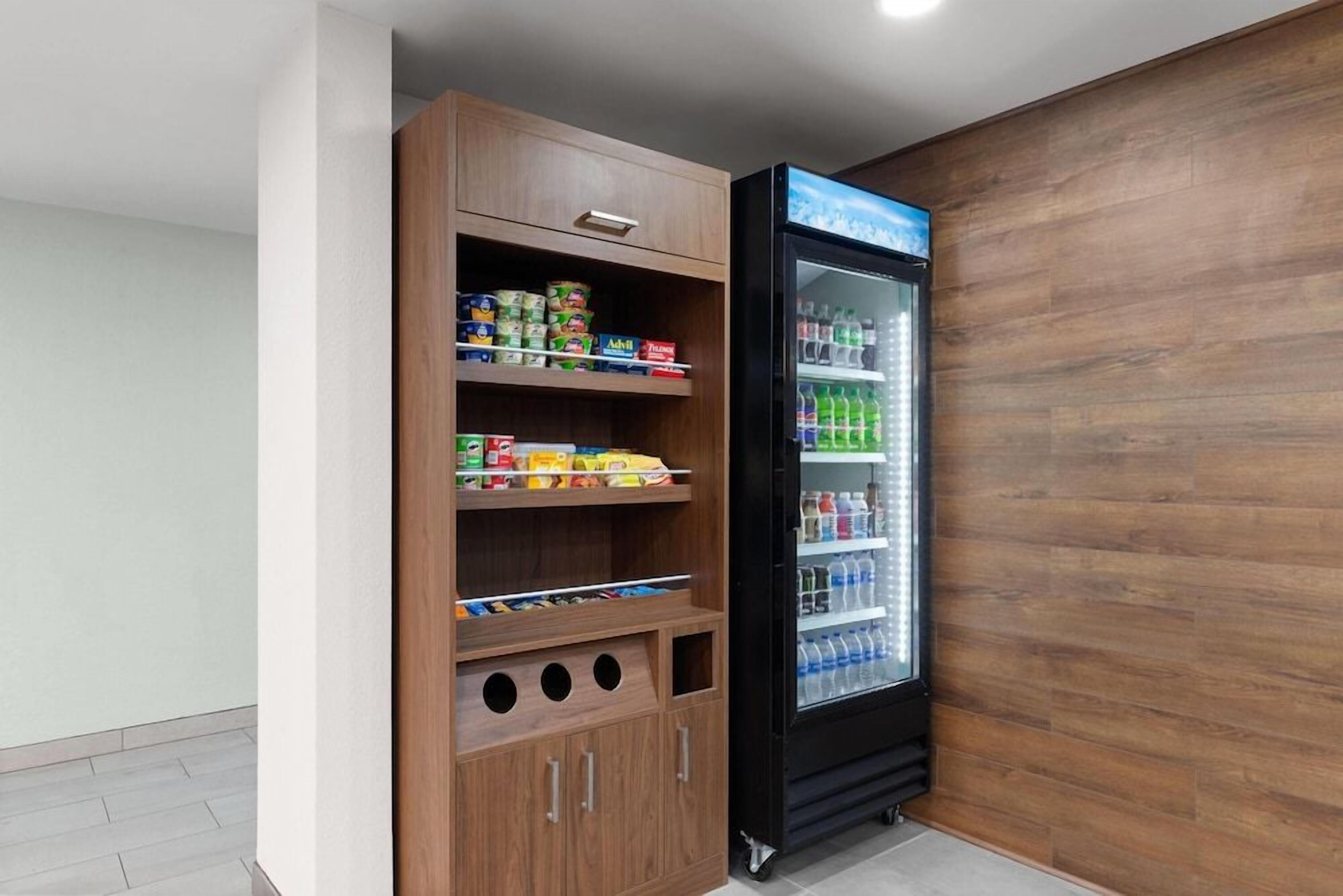 A vending machine with a variety of snacks and drinks, adjacent to a wooden cabinet with multiple shelves.