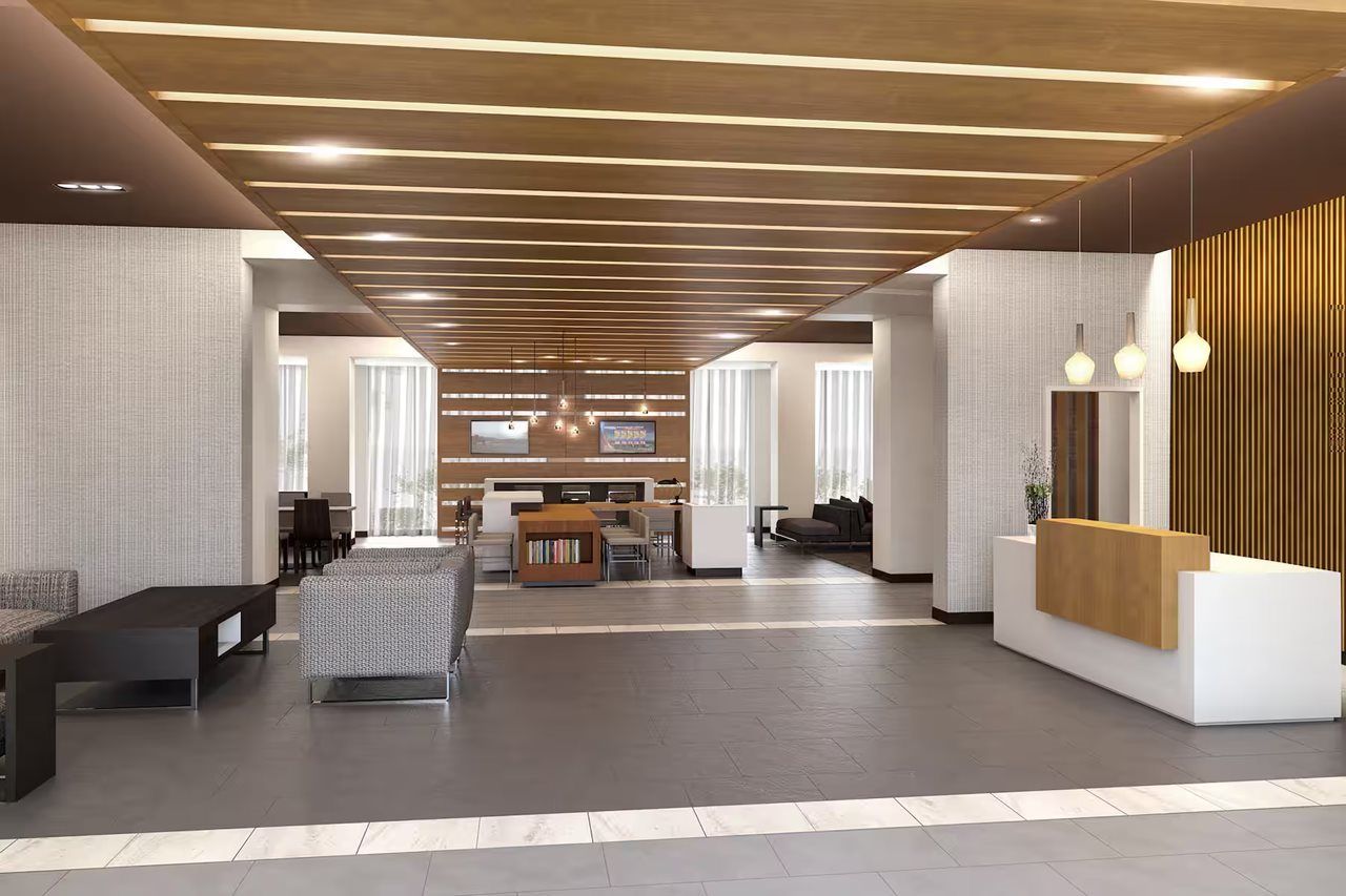 A modern lobby with a reception desk, seating area, and a television screen.