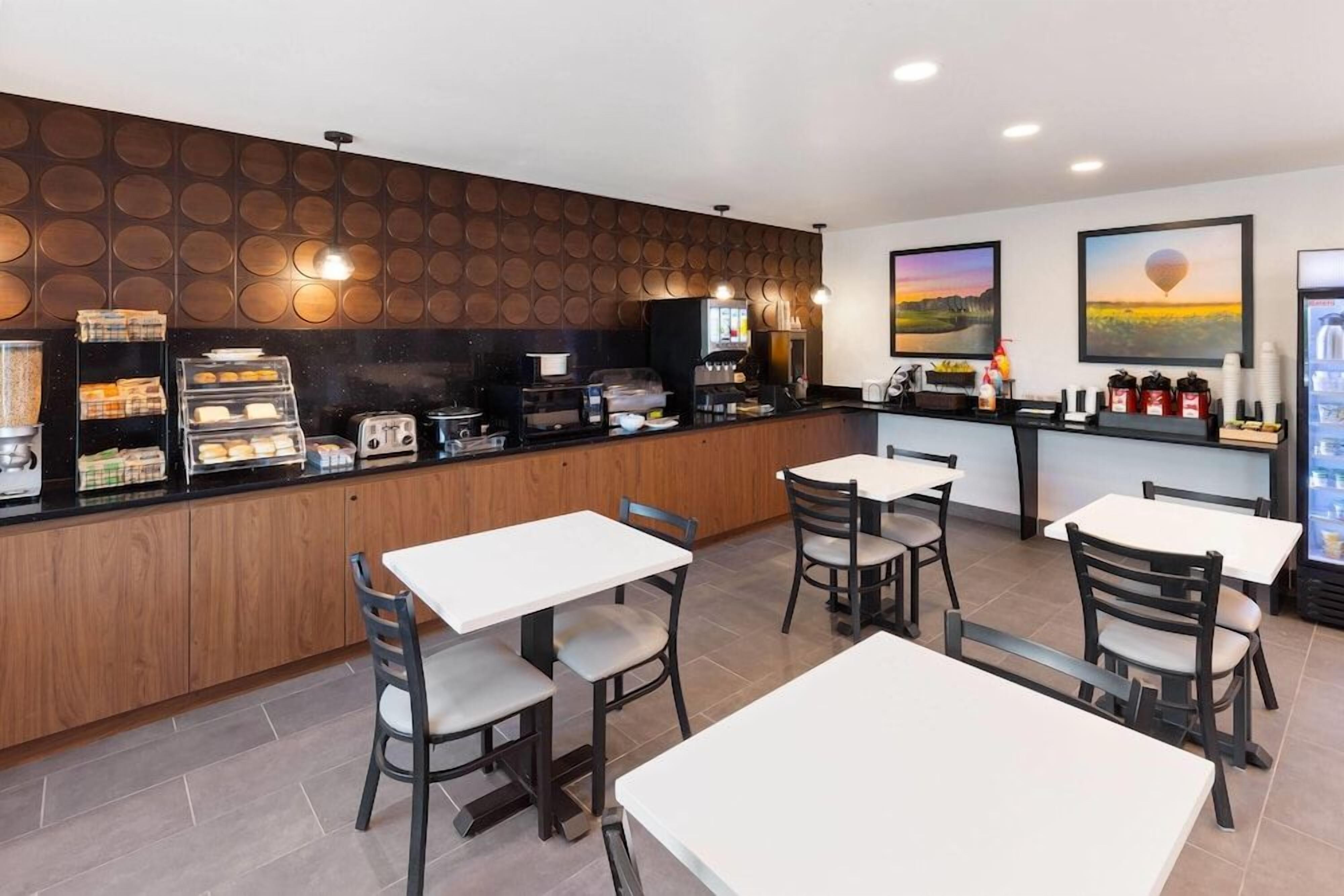 A restaurant with a counter, tables, chairs, and a wall with circular patterns.