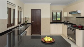 A kitchen with a central island, a stove, and a sink. - Dubai Creek Club Villas (Dubai)
