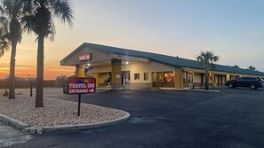 A Travel Inn with a clear entrance sign, a parking lot, and a building with a flat roof. - Unadilla/perry Near I-75 (Unadilla)