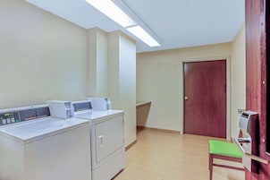 Un lavadero con dos lavadoras, un banco y una puerta.