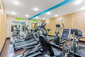 Un gimnasio con cintas de correr, elípticas y un espejo grande.