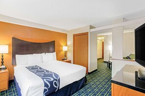 Ein Hotelzimmer mit einem Bett, Nachttischen, einem Fernseher und einer Tür zu einem Flur.