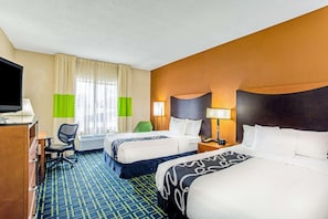 A hotel room with two beds, a desk, a chair, a television, and a window with curtains. - Manassas Hotel (Manassas)