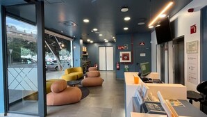 A modern hotel lobby with seating, a reception desk, and an elevator. - Easyhotel Malaga City Centre (Málaga)