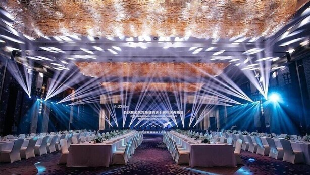 A banquet hall with rows of tables, a stage with a backdrop, and a patterned carpet. - Kempinski Hotel Changsha (Changsha)