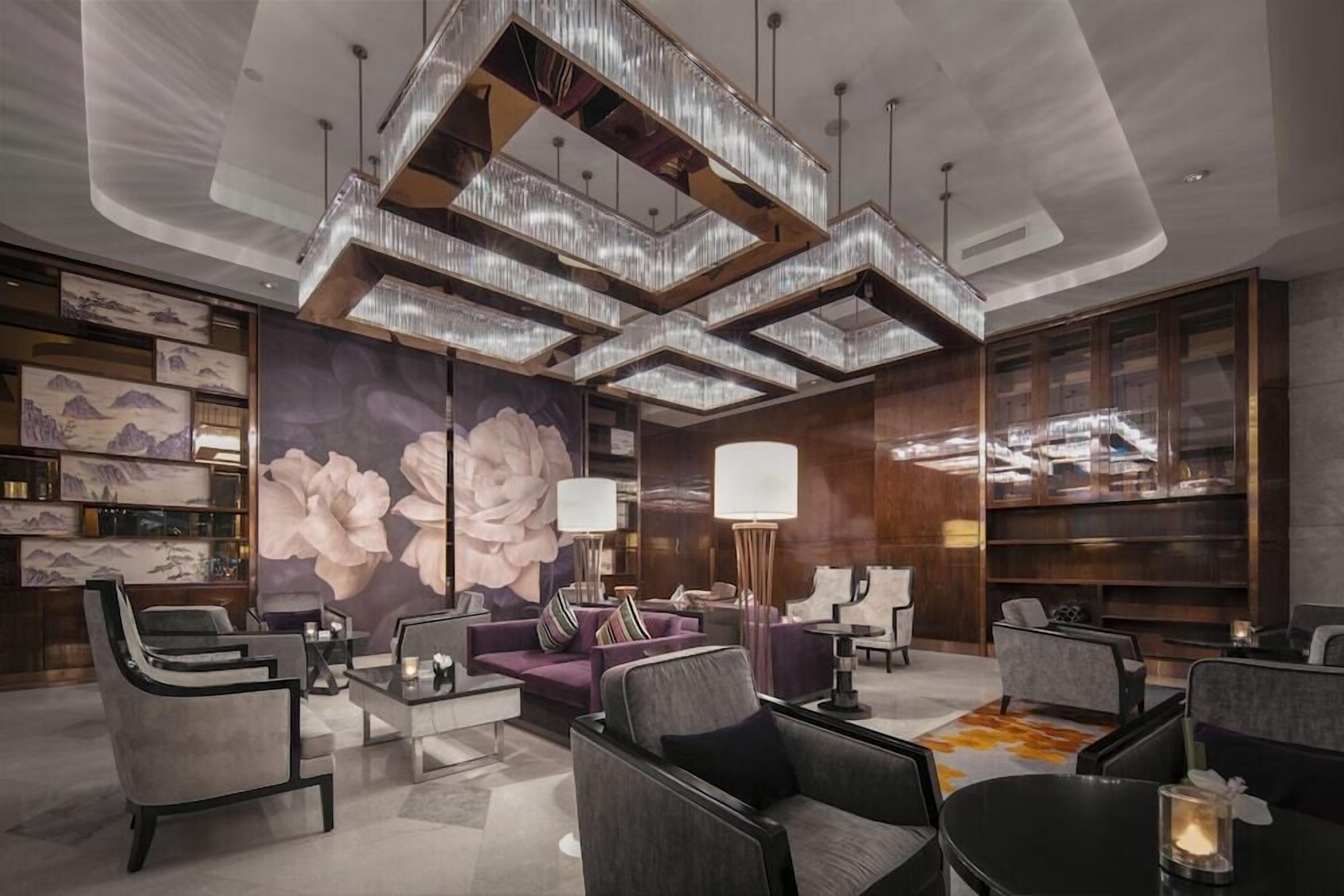 A modern lobby with a central seating area, a large floral mural, and a unique ceiling design.