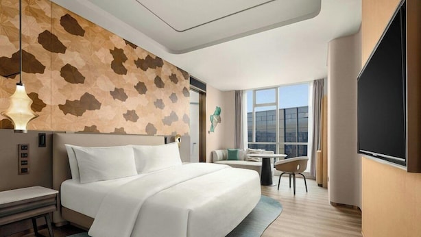 A hotel room with a large bed, a desk, a chair, a small table, and a large window. - Kempinski Hotel Changsha (Changsha)