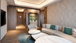 A modern hotel room with a sofa, two round coffee tables, a TV, and a kitchenette area. - Kempinski Hotel Changsha (Changsha)