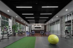 A gym with exercise equipment, a green mat, and a yellow exercise ball. - Kempinski Hotel Changsha (Changsha)