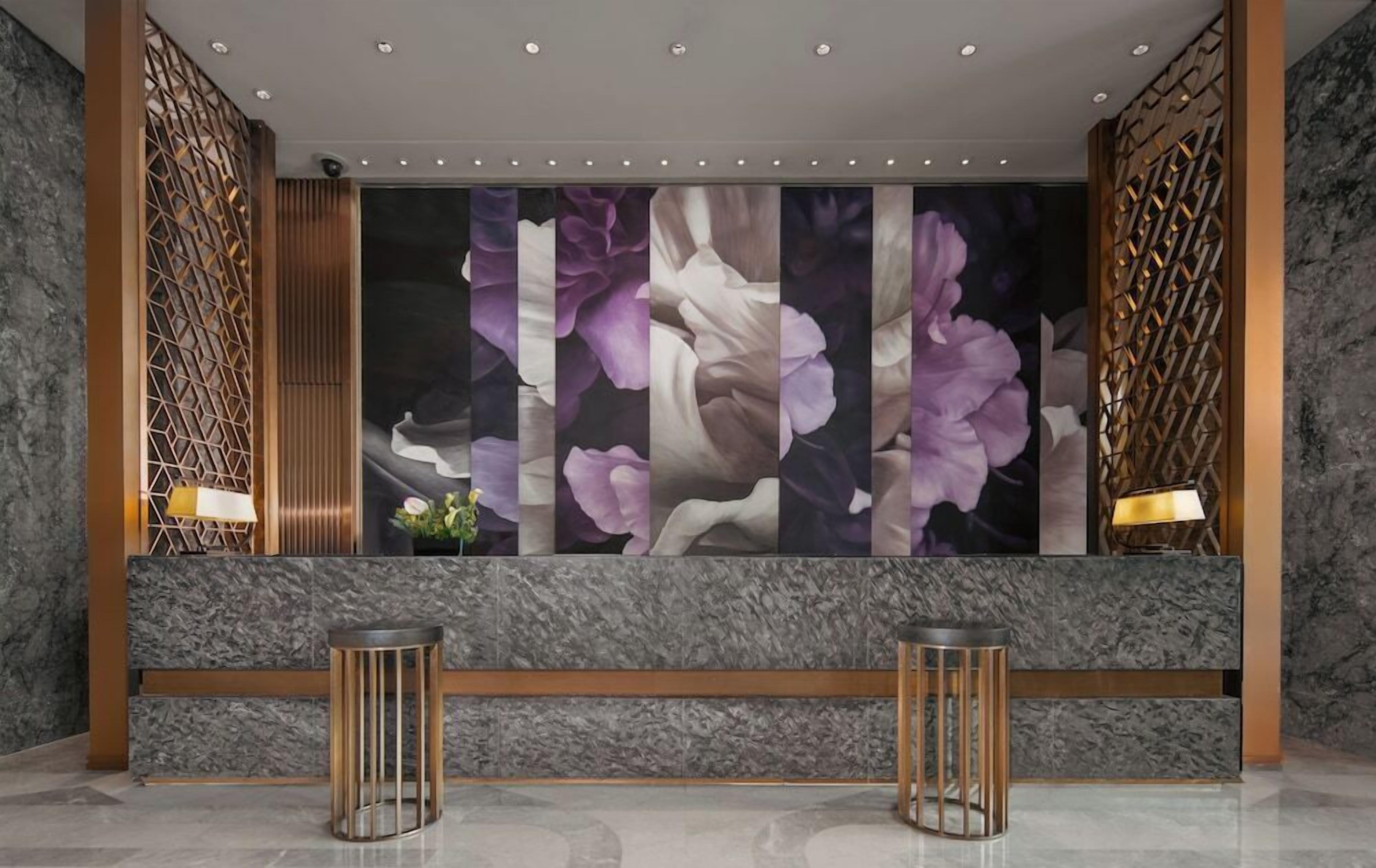 Un vestíbulo con un amplio mural floral, dos mesas redondas y una pared con estampado.