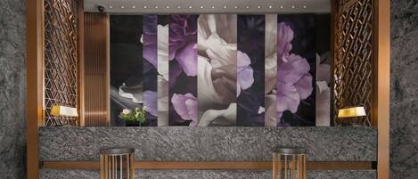 Un vestíbulo con un amplio mural floral, dos mesas redondas y una pared con estampado.