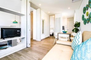 A modern living room with a TV, a dining area with a table and chairs, and a kitchen in the background. - Azure Lofts And Pool (San Andrés)