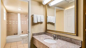 A bathroom with a bathtub, toilet, sink, and a large mirror. - Econo Lodge Del Rio, TX (Del Rio)