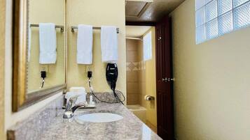 A bathroom with a sink, mirror, towel rack, and a hairdryer.