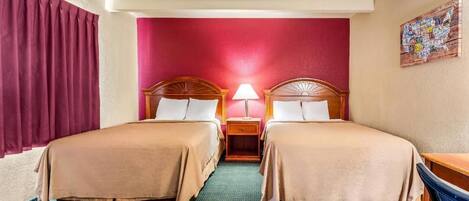 A hotel room with two beds, a nightstand with a lamp, a desk, and a wall map.