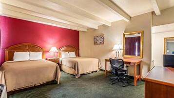A hotel room with two beds, a desk, a chair, and a mirror.