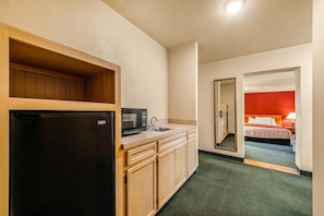 A compact hotel room with a kitchenette, a bed, and a mirror reflecting the room. - Econo Lodge Del Rio, TX (Del Rio)