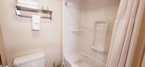 A bathroom with a toilet, a shower with a glass door, and a towel rack with towels. - Red Deer City Centre (Red Deer)