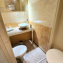 Un baño con lavamanos blanco, inodoro y un pequeño cubo de basura.